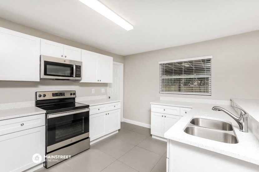 a white kitchen with stainless steel appliances and white cabinets