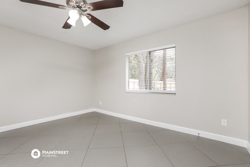 an empty room with a ceiling fan and a window