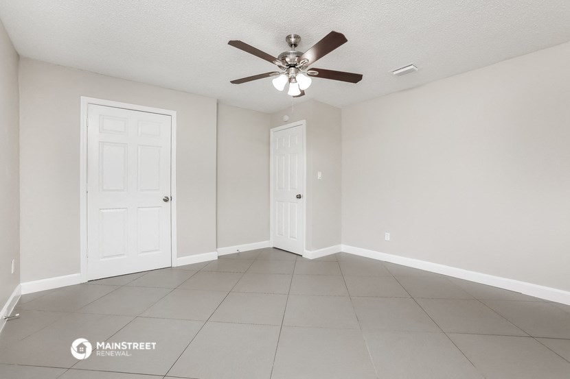 the spacious living room with ceiling fan and tiled floor