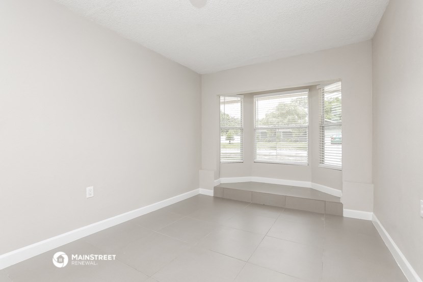 an empty living room with a large window and a tiled floor