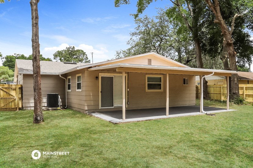 a small tan house with a porch and a yard