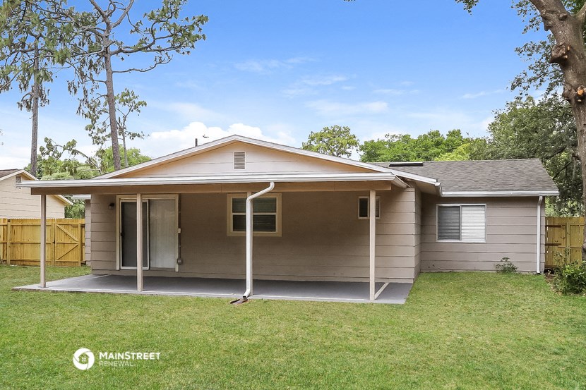 a small tan house with a porch and a yard