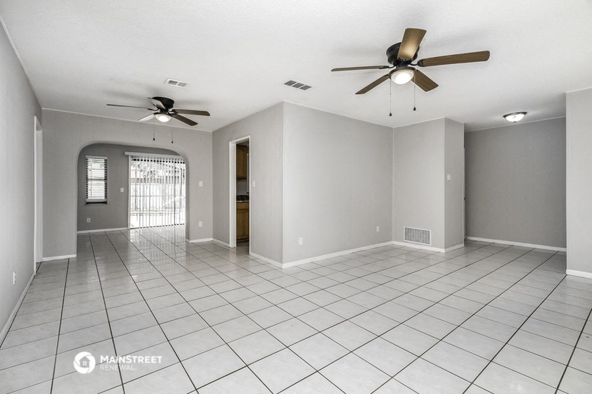 an empty living room with two ceiling fans and a tiled floor