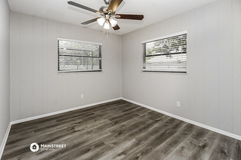 the bedroom has a large window and a ceiling fan