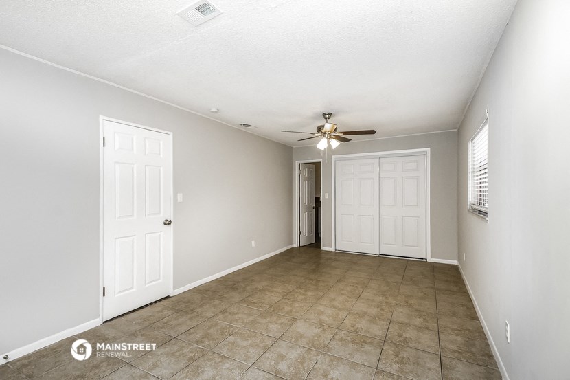 an empty living room with a ceiling fan and a door to a closet