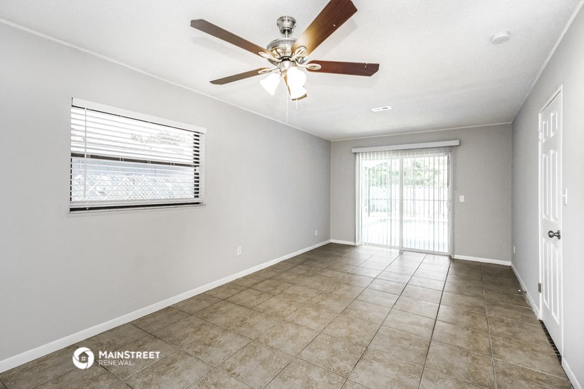 an empty living room with a ceiling fan and a window
