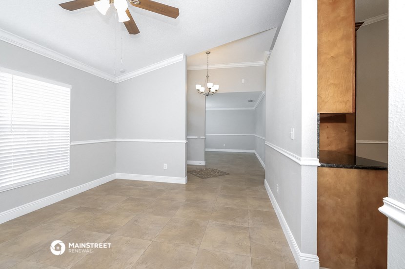the living room and dining room of an empty house with a ceiling fan