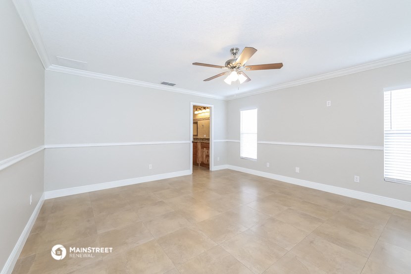 the spacious living room with ceiling fan and tile flooring