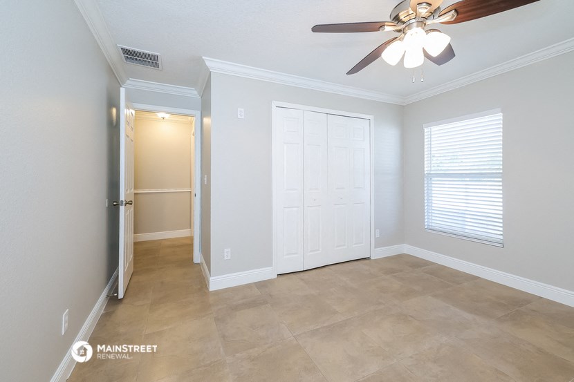 the living room with a closet and a ceiling fan