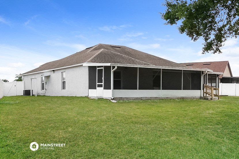 a white house with a grass yard and a tree
