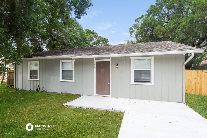 a small gray house with a yard and a door