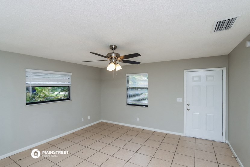 the living room has a ceiling fan and a tiled floor