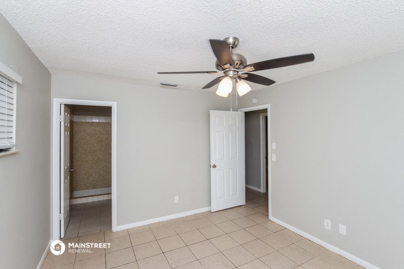 a living room with a ceiling fan and a door to a bathroom