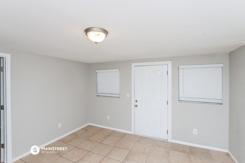 the spacious living room with tile flooring and a white door