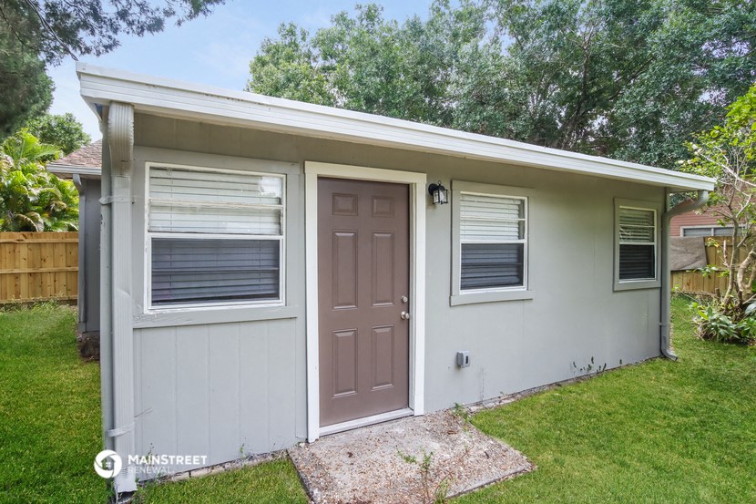 a small white house with a brown door and two windows