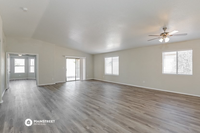 the living room of an empty house with a ceiling fan