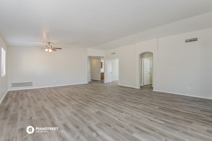 a spacious living room with white walls and a ceiling fan