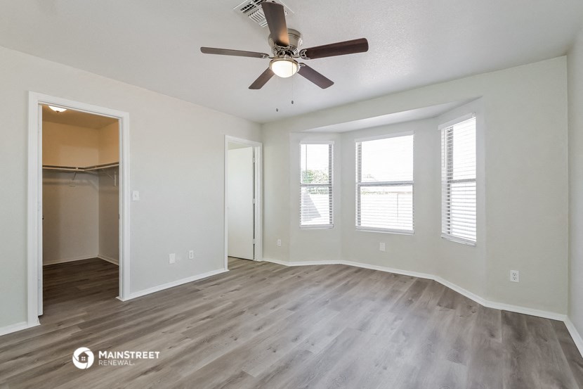 an empty living room with a ceiling fan and windows