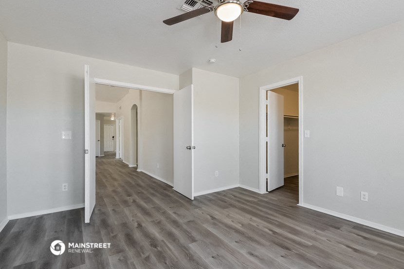 the living room of an apartment with white walls and a ceiling fan