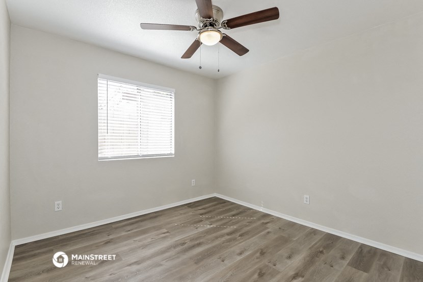 the spacious living room with wood flooring and a ceiling fan
