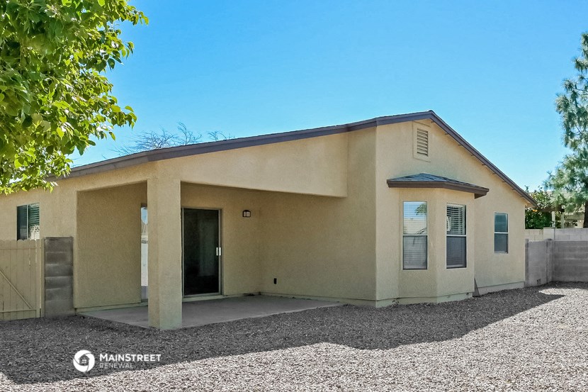 a beige house with a driveway and a tree