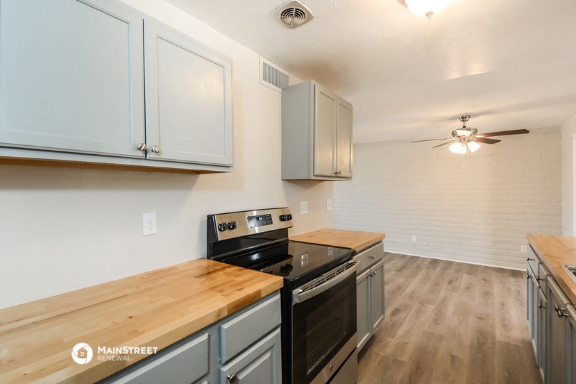 a kitchen with white cabinets and a stove and a ceiling fan