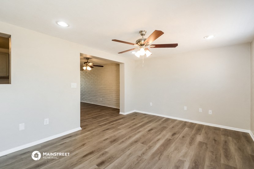 the spacious living room with ceiling fan and wood flooring