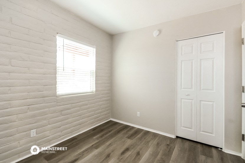 a bedroom with white walls and wood flooring and a white door