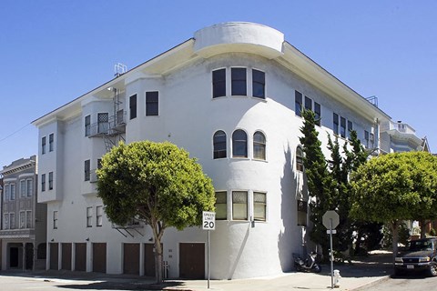 A white building with a round section on the top floor.