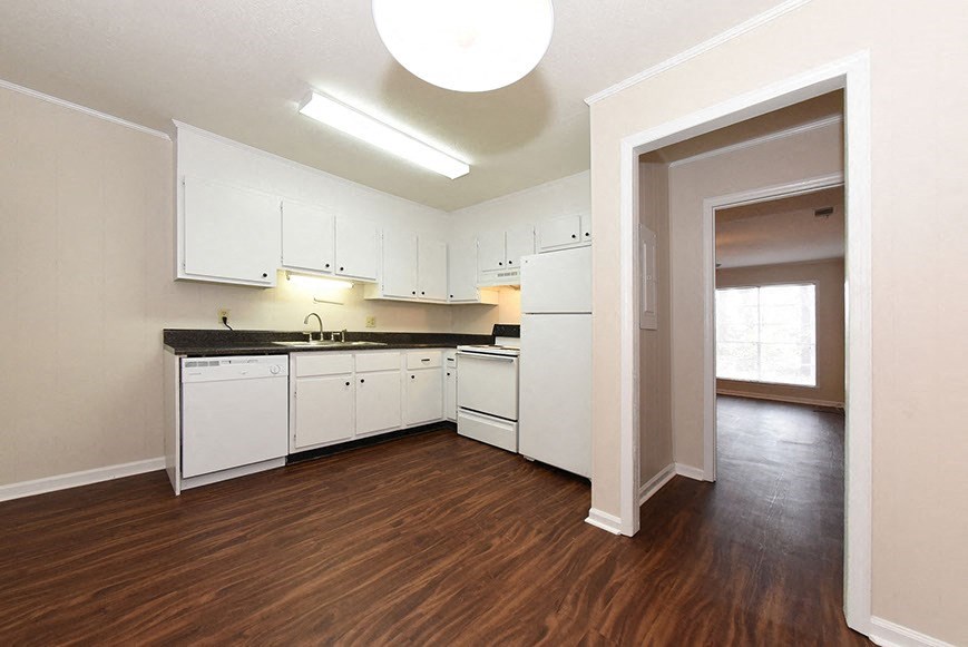 an empty kitchen with white cabinets and a wood floor