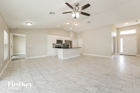 A spacious living room with a ceiling fan and tiled flooring.