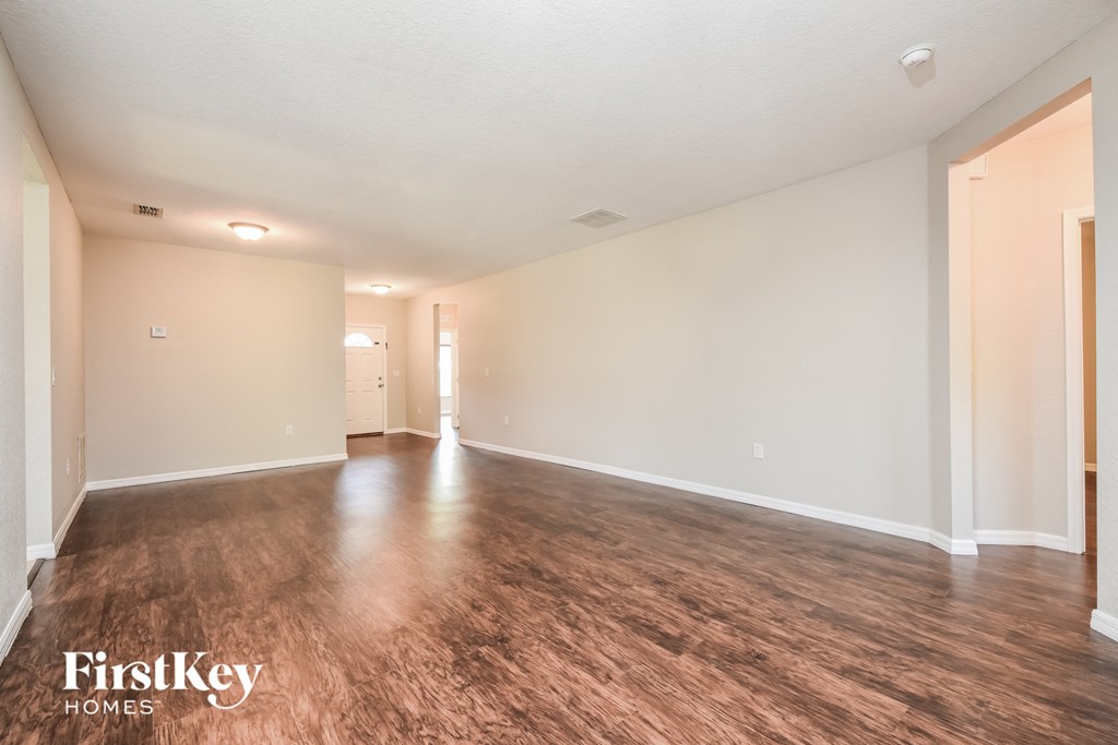the living room and dining room of an empty house with wood flooring
