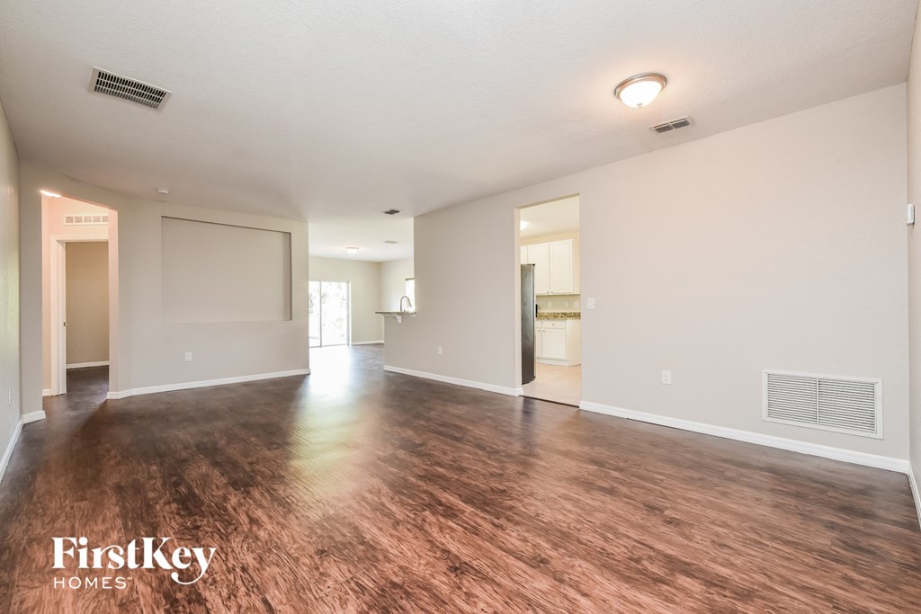 the living room and dining room of an apartment with wood flooring and white walls