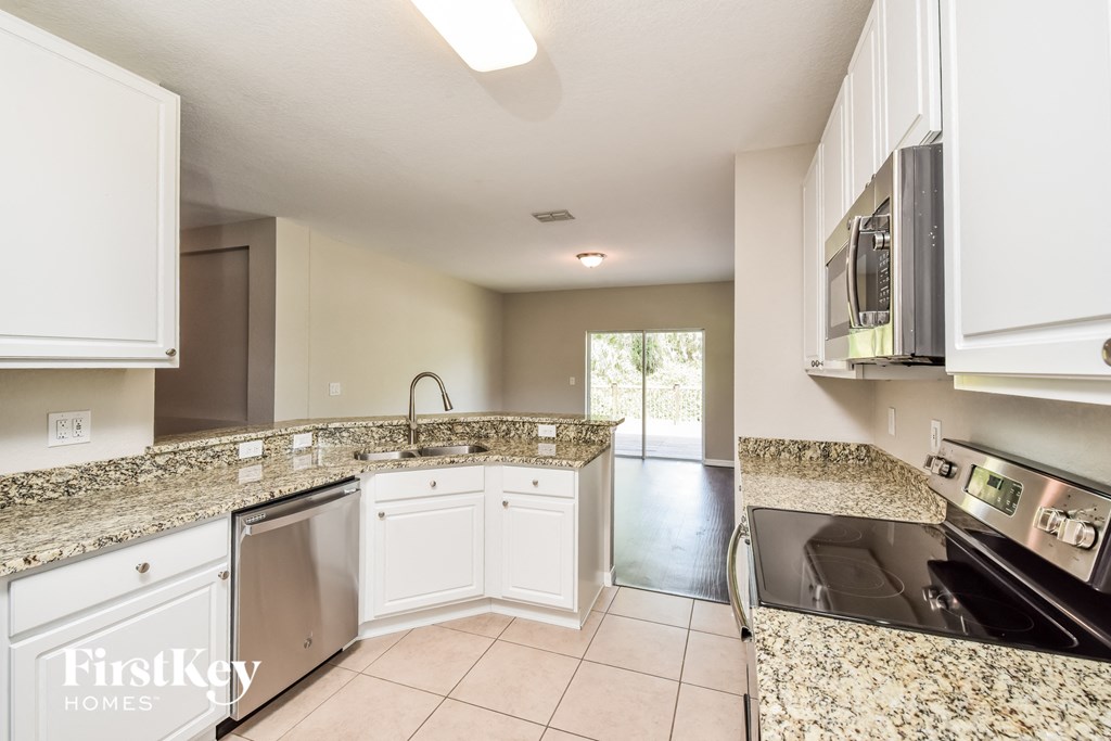 a kitchen with white cabinets and granite counter tops