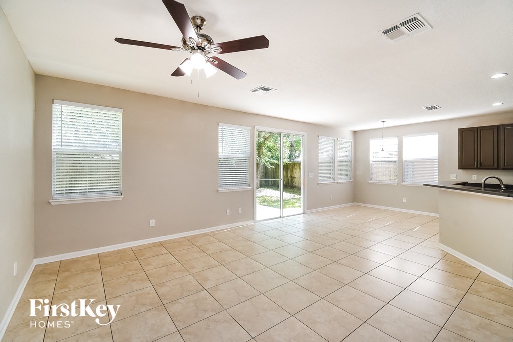 an empty living room and kitchen with a ceiling fan