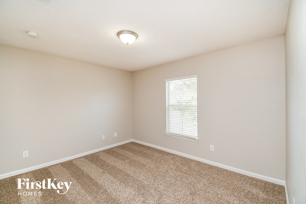 the spacious bedroom with carpeted flooring and a large window