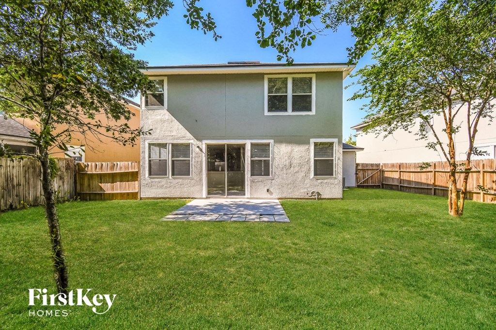 a gray house with a yard and a fenced in backyard