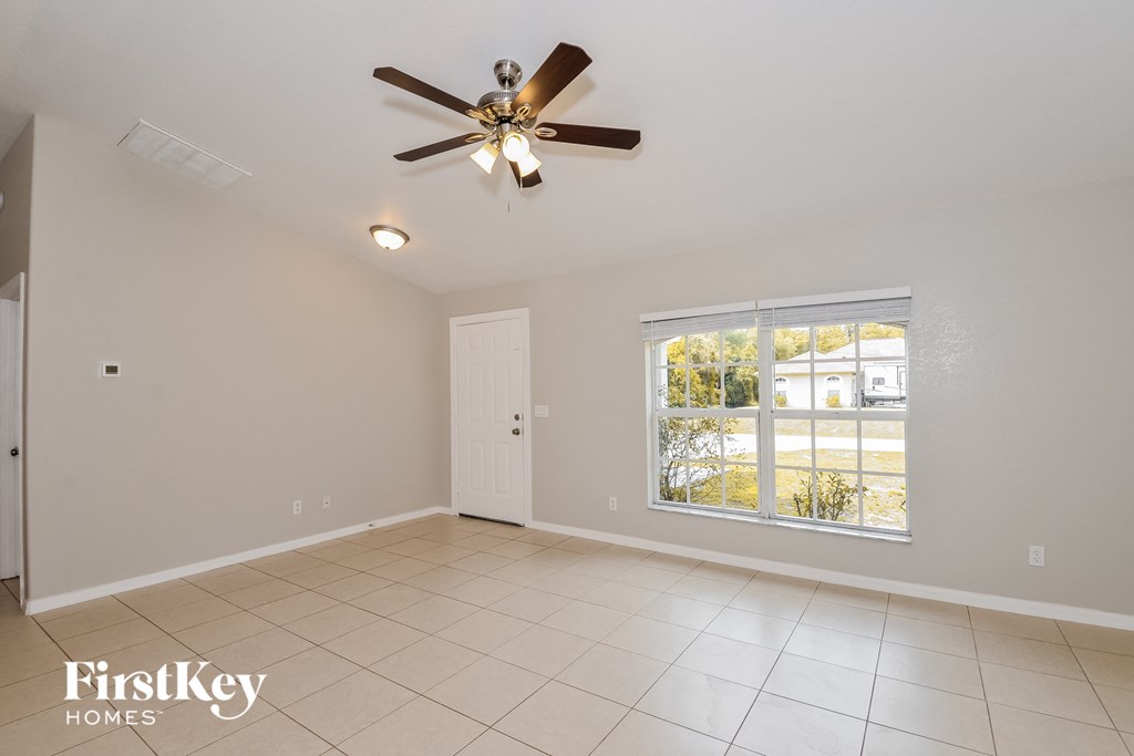 A spacious room with a ceiling fan and a window showing an outdoor view.