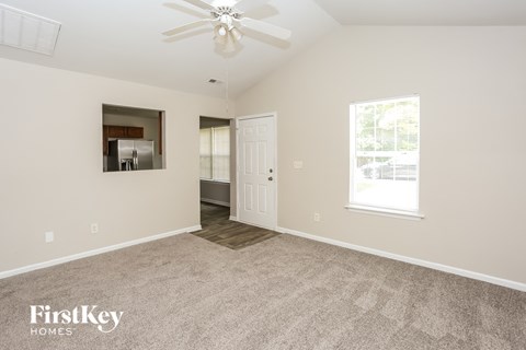 a spacious living room with carpet and a ceiling fan