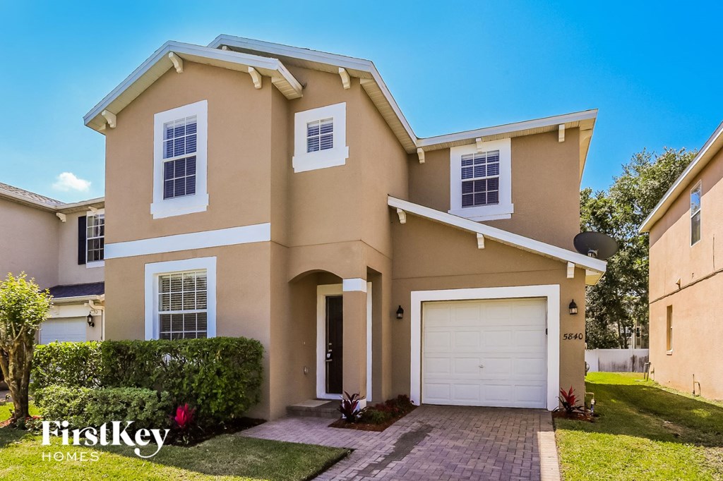 a beige house with a garage door and a lawn