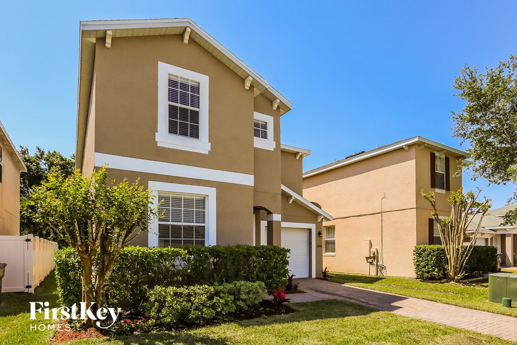a beige and white house with a yard and a driveway