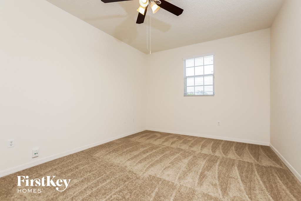the spacious living room with carpeting and a ceiling fan