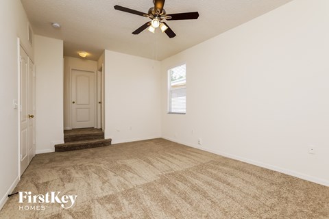 a living room with carpet and a ceiling fan