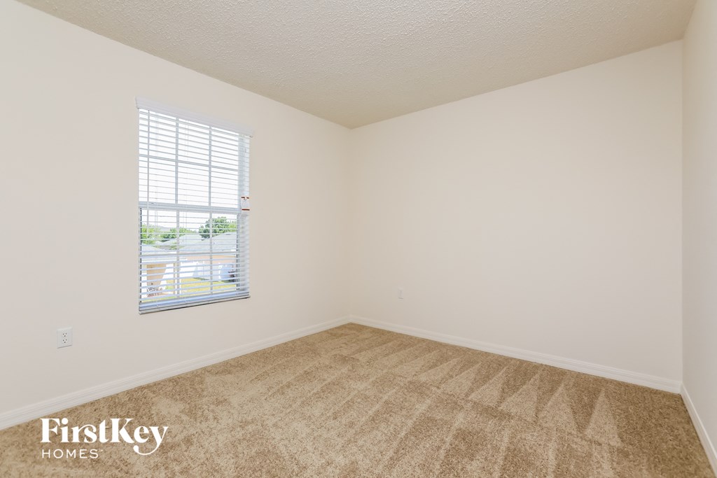 a bedroom with a window and a carpeted floor