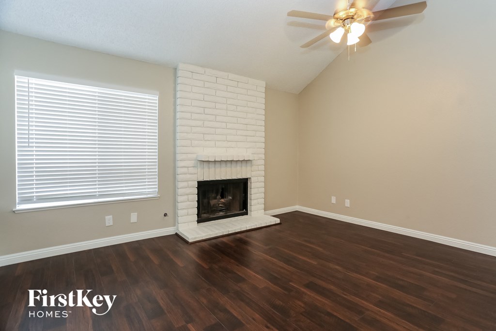 the living room has a brick fireplace and wood flooring