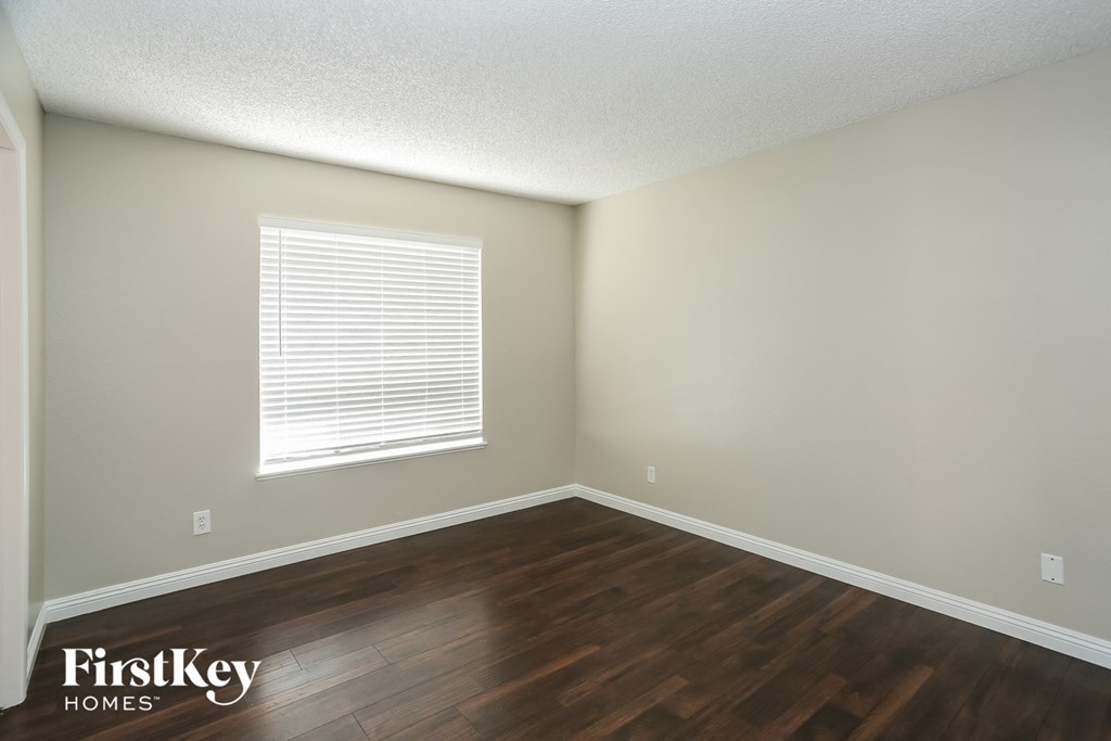an empty room with wood floors and a window