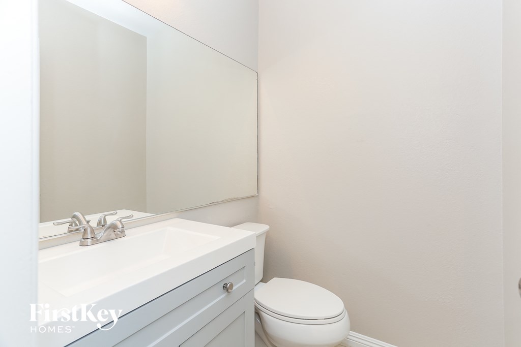 a white bathroom with a sink toilet and mirror