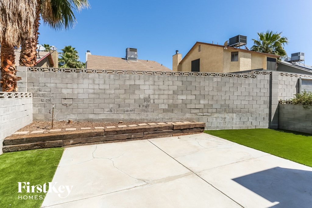 a backyard with a retaining wall and a patio and grass