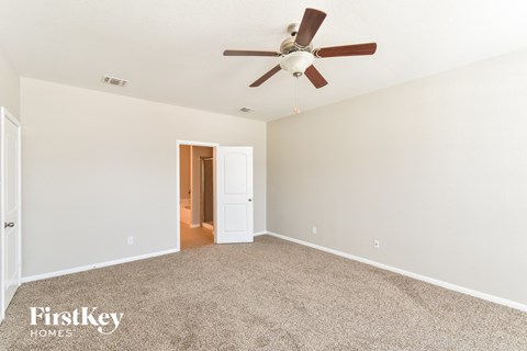 a spacious living room with carpet and a ceiling fan