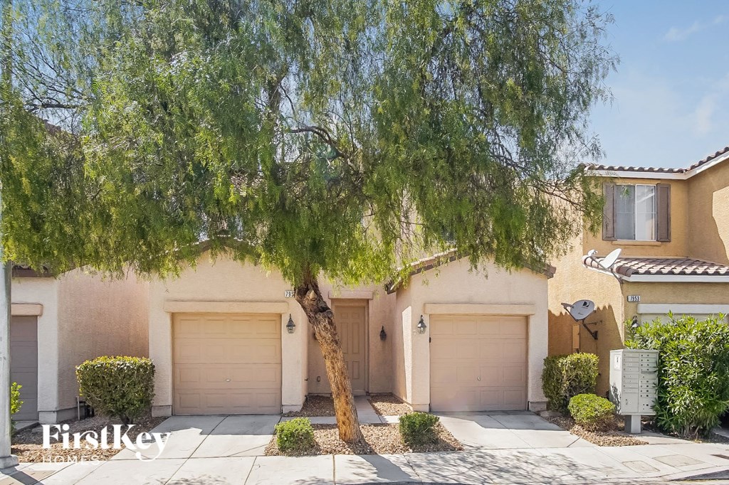 a house with two garage doors and a tree in front of it